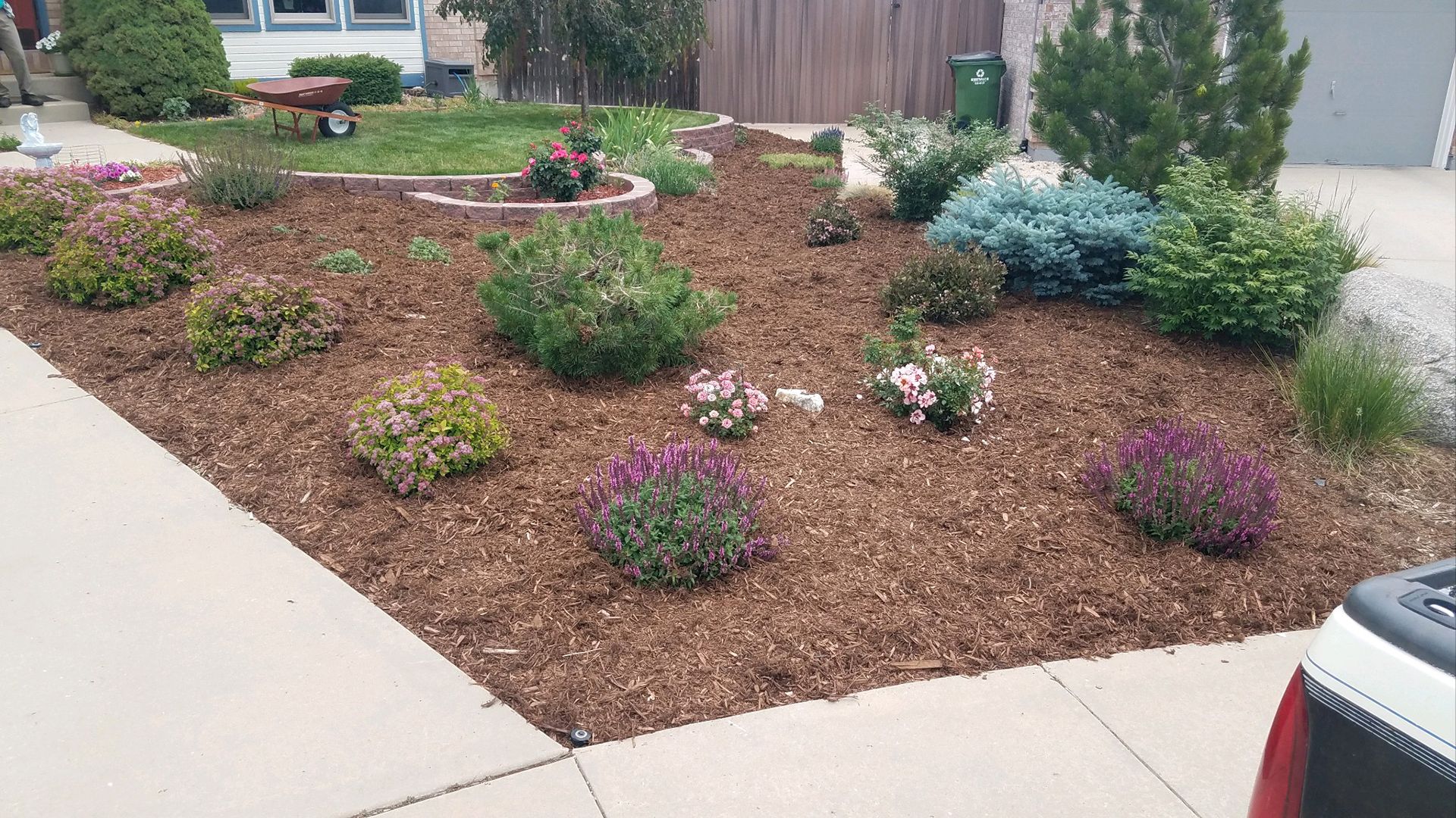 A garden with flowers and mulch in front of a house.