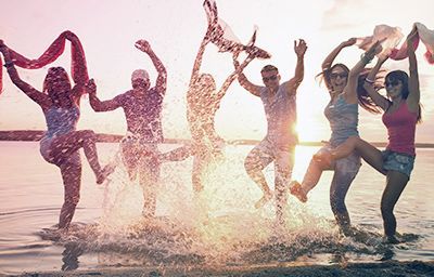 a group of people are jumping into the water on the beach