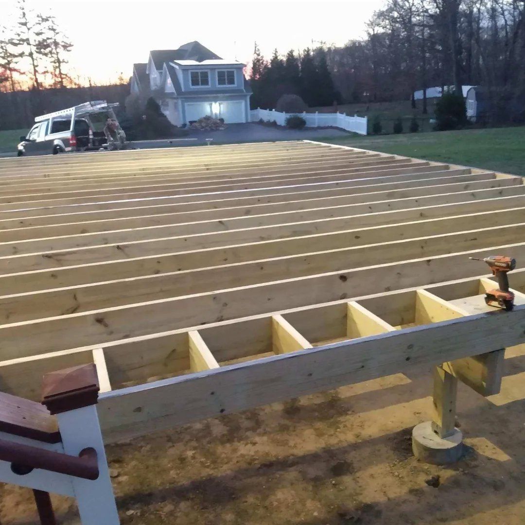 A wooden deck under construction with a house in the background