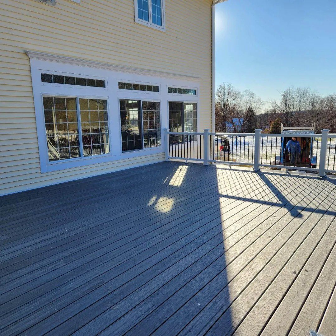 A deck with a railing and a house in the background