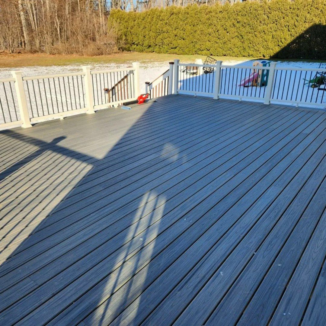 A wooden deck with a white railing and stairs leading to it.