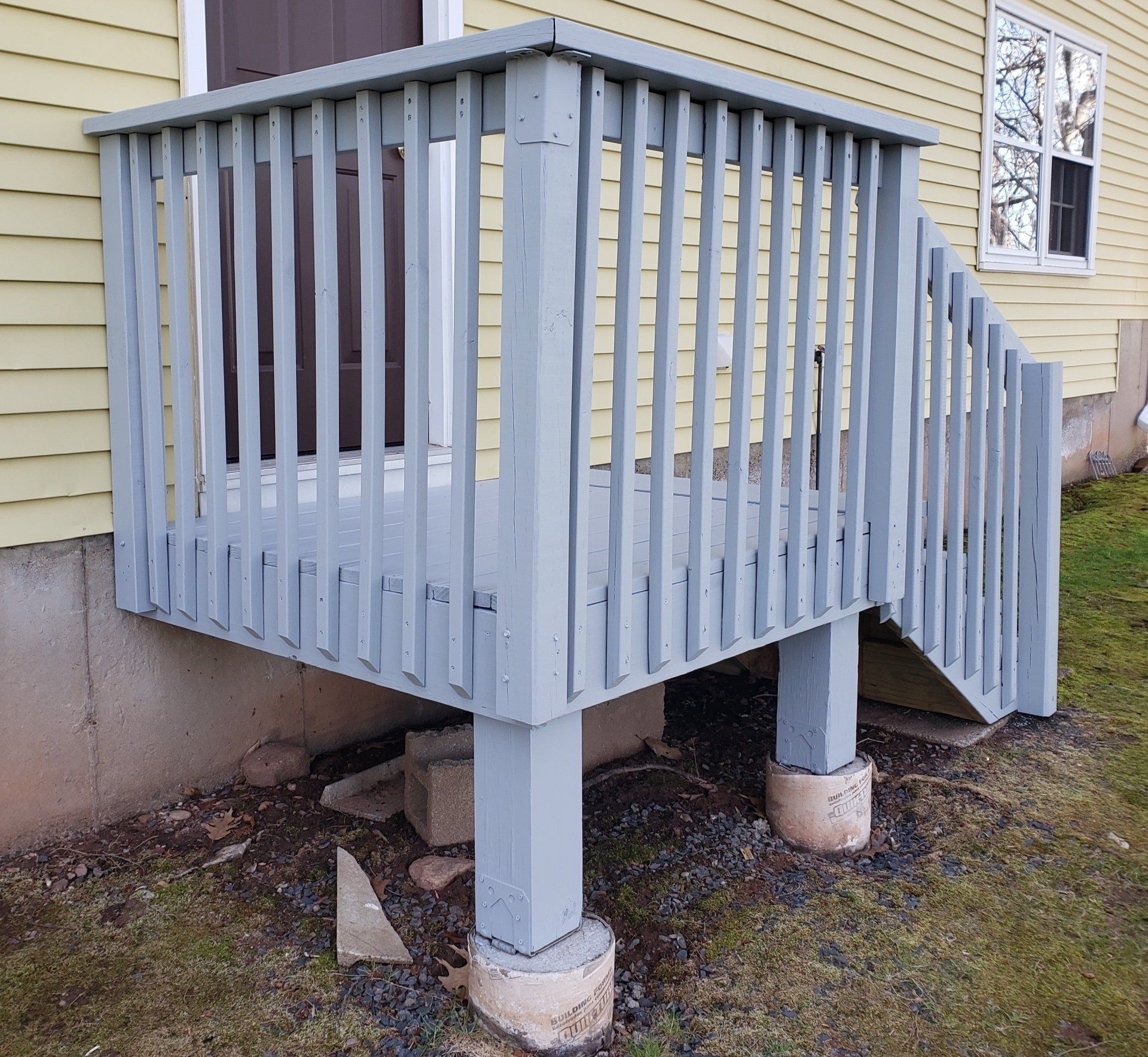 A wooden deck with stairs leading up to it is outside of a house.