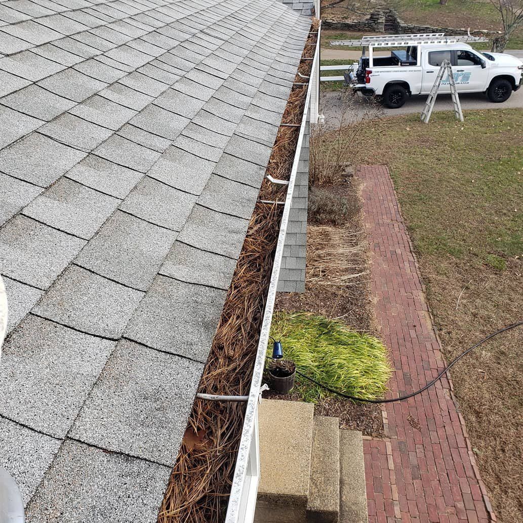 A white truck is parked on the side of a house next to a gutter.