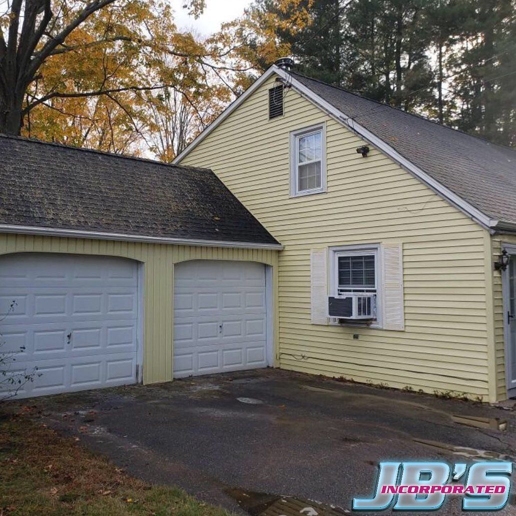 A yellow house with white garage doors and a jd 's logo on the side