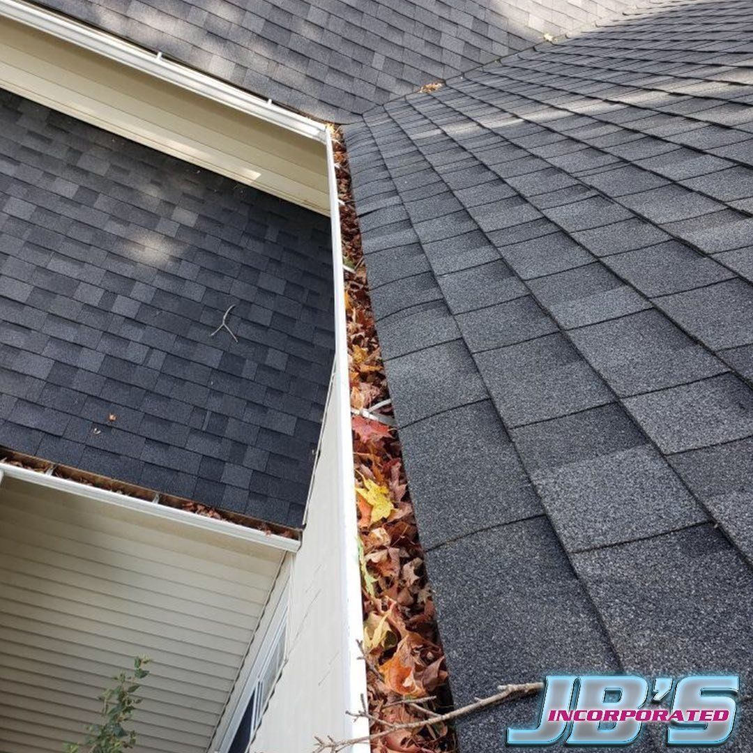 A gutter filled with leaves is on the side of a house.