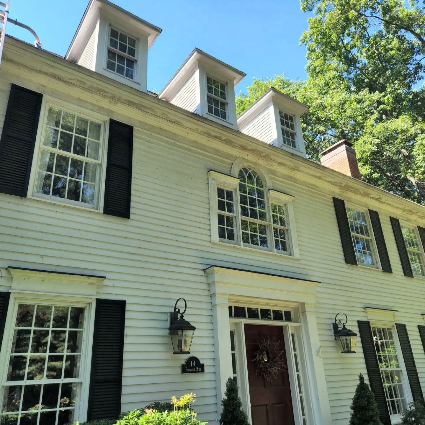 A white house with black shutters and a red door