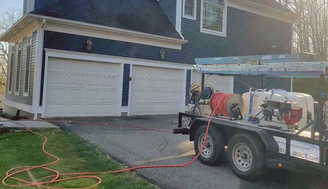 A trailer with a hose attached to it is parked in front of a house.