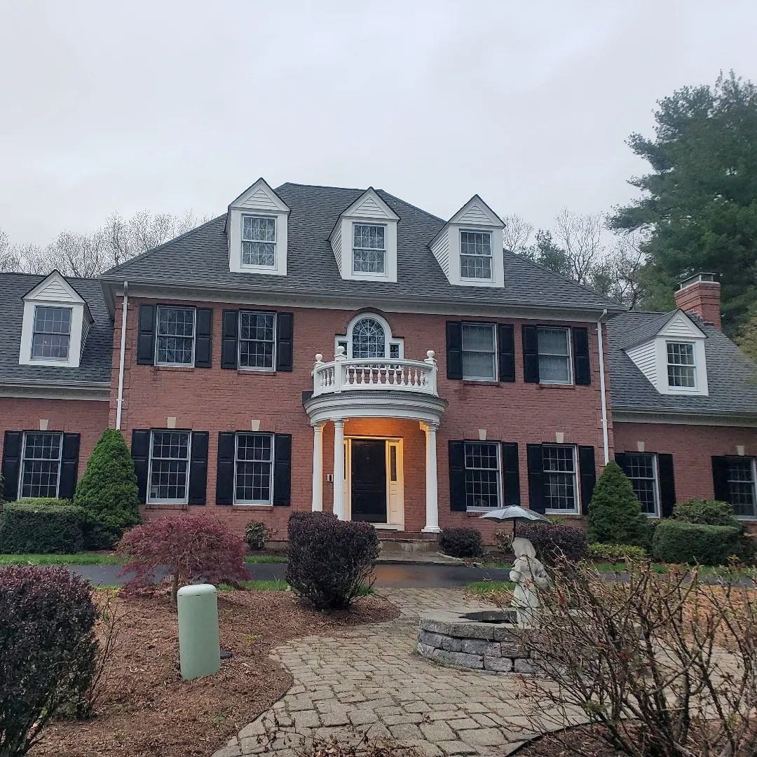 A large brick house with black shutters and a statue in front of it.