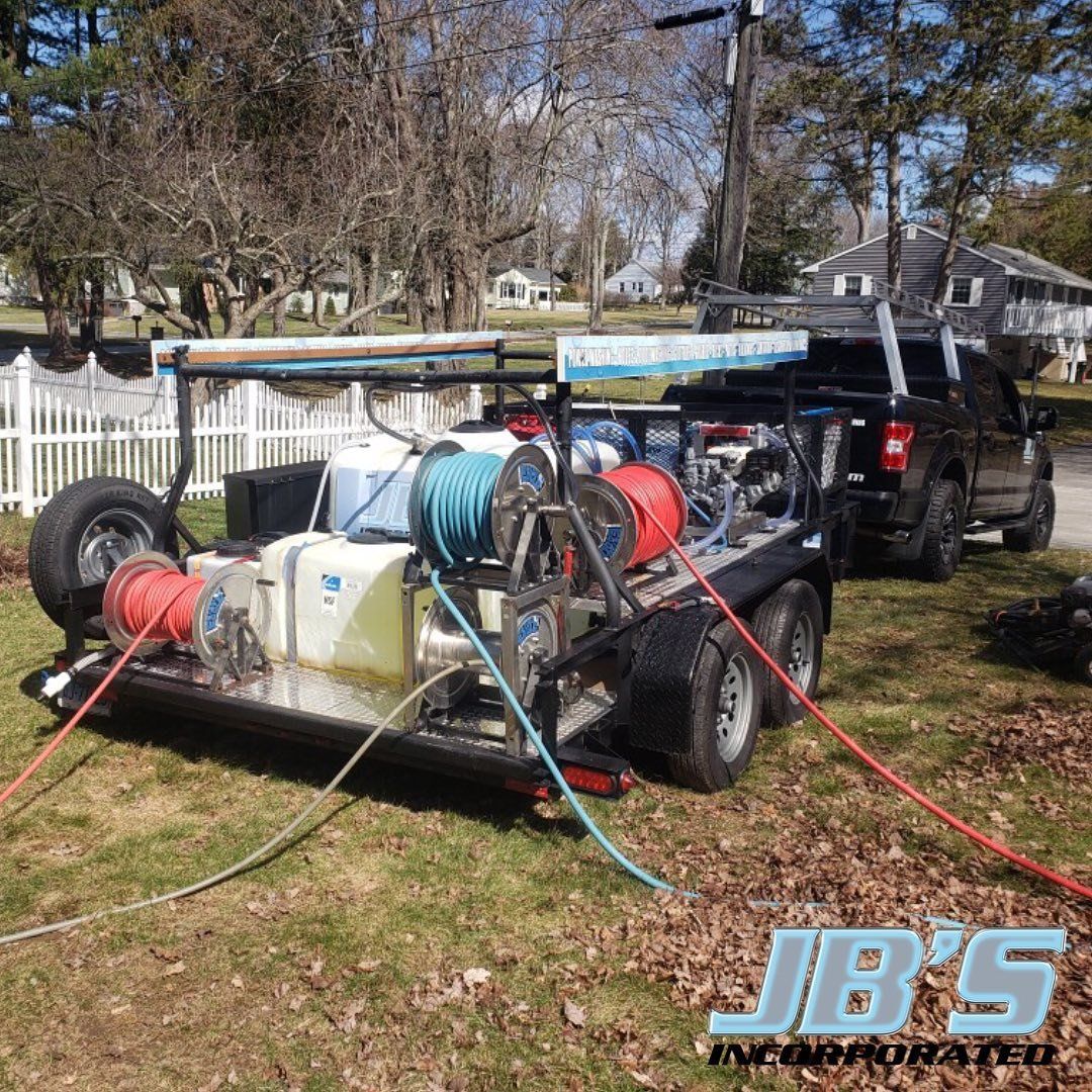 A trailer with a hose reel attached to it is parked next to a truck.