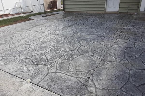 Stamped concrete driveway in front of a garage and building entrance.