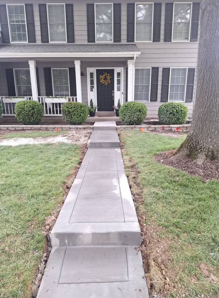 Front walkway to a gray two-story house with a black front door and small porch.