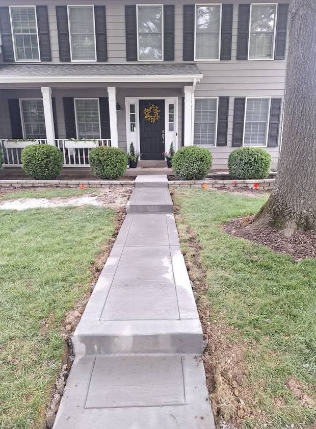 Front walkway to a gray two-story house with white trim and a black front door.