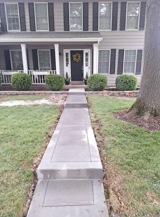 Front walkway to a gray two-story house with white trim and a black front door.