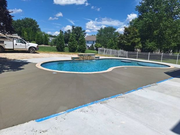 Backyard pool with blue water, concrete deck, trees, and a white truck nearby