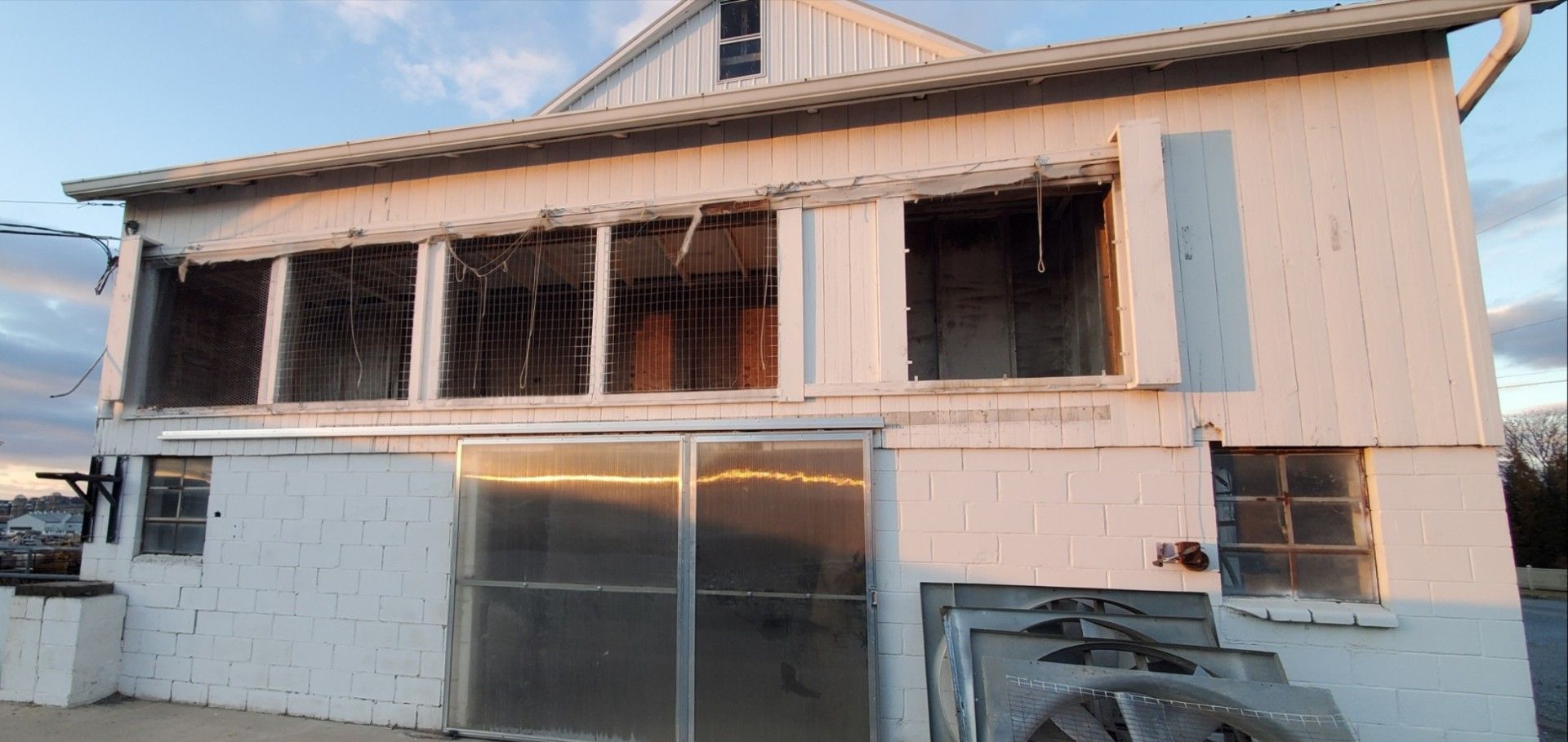 A two-story building with a white cinder block base, a large ground-level sliding door, and a missing upper-level porch.