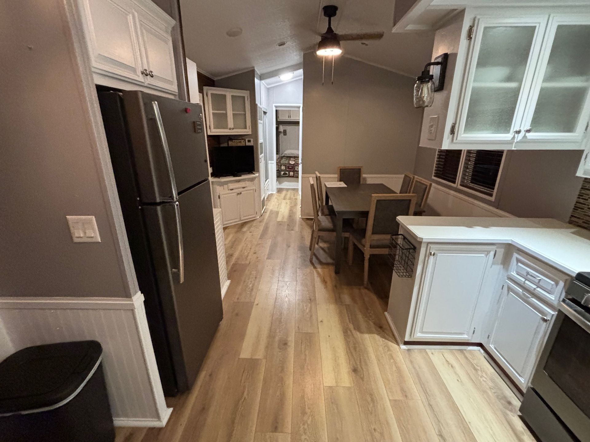 Interior view of a kitchen and dining area with cabinets, appliances, and a table with chairs.