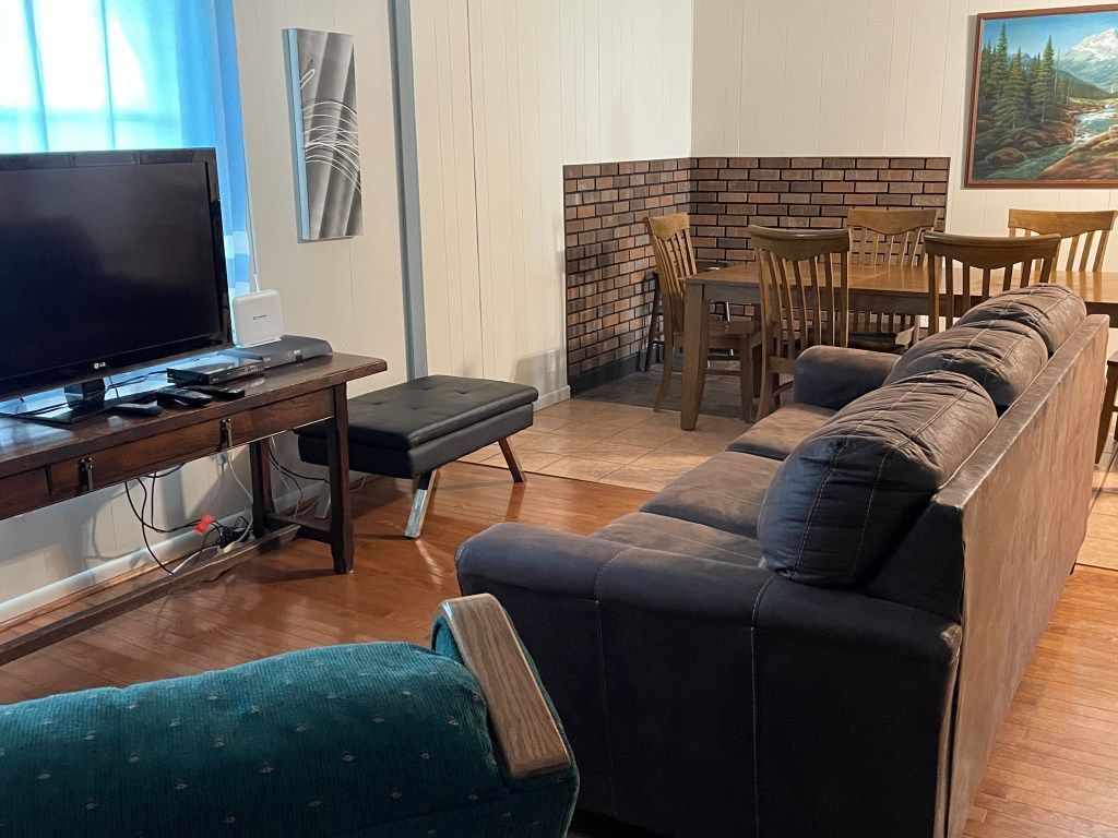 Living room with sectional sofa, TV, fireplace, and dining table on hardwood floor