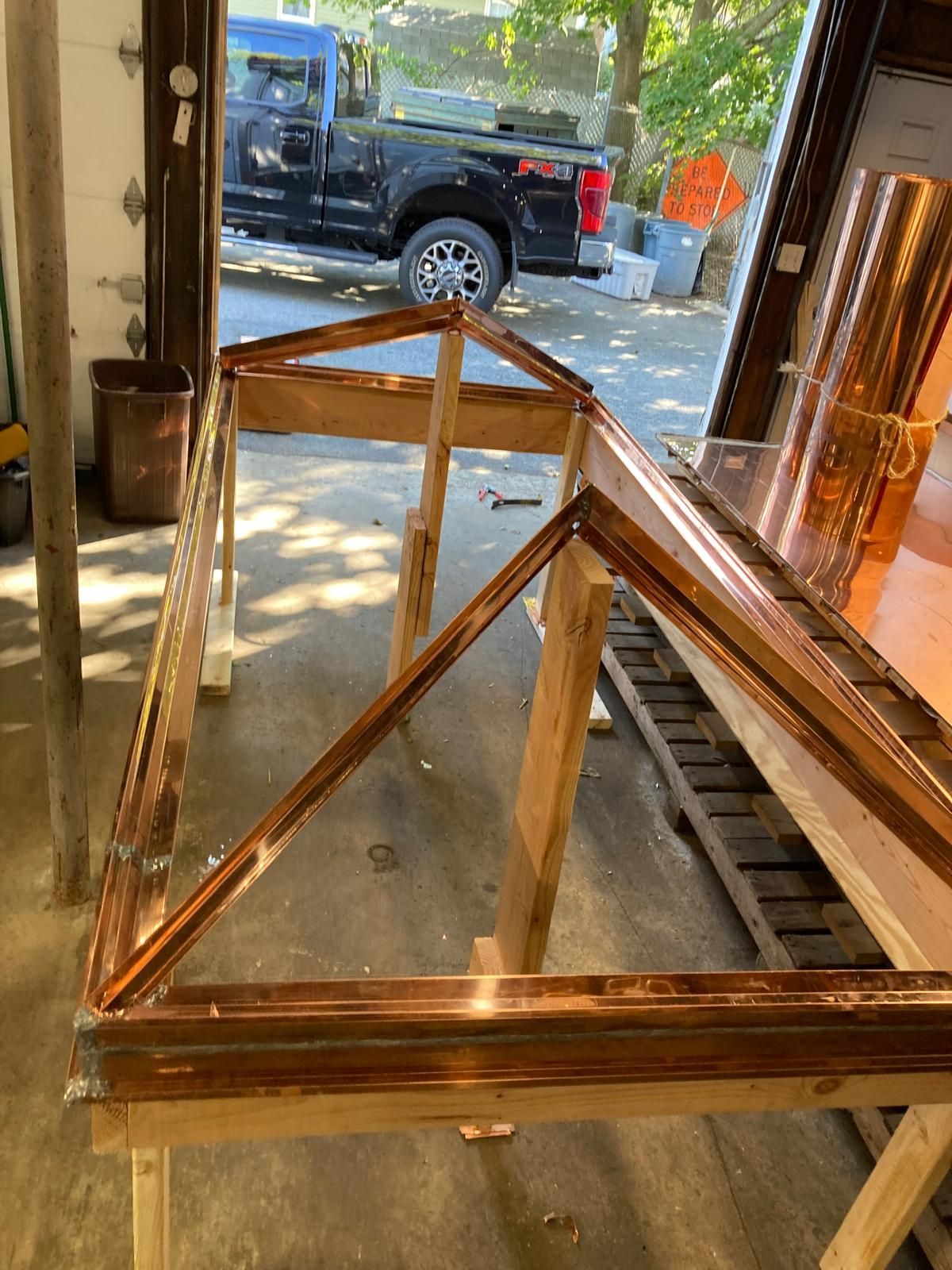 A copper frame is sitting on top of a wooden table in a garage.