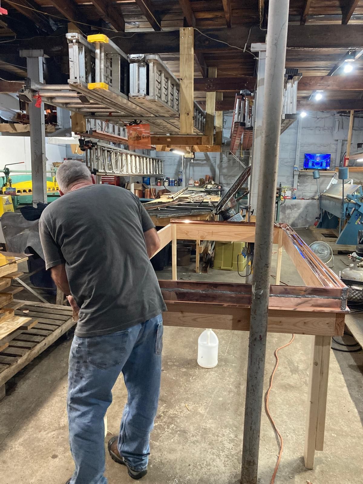 A man is working on a wooden table in a workshop.
