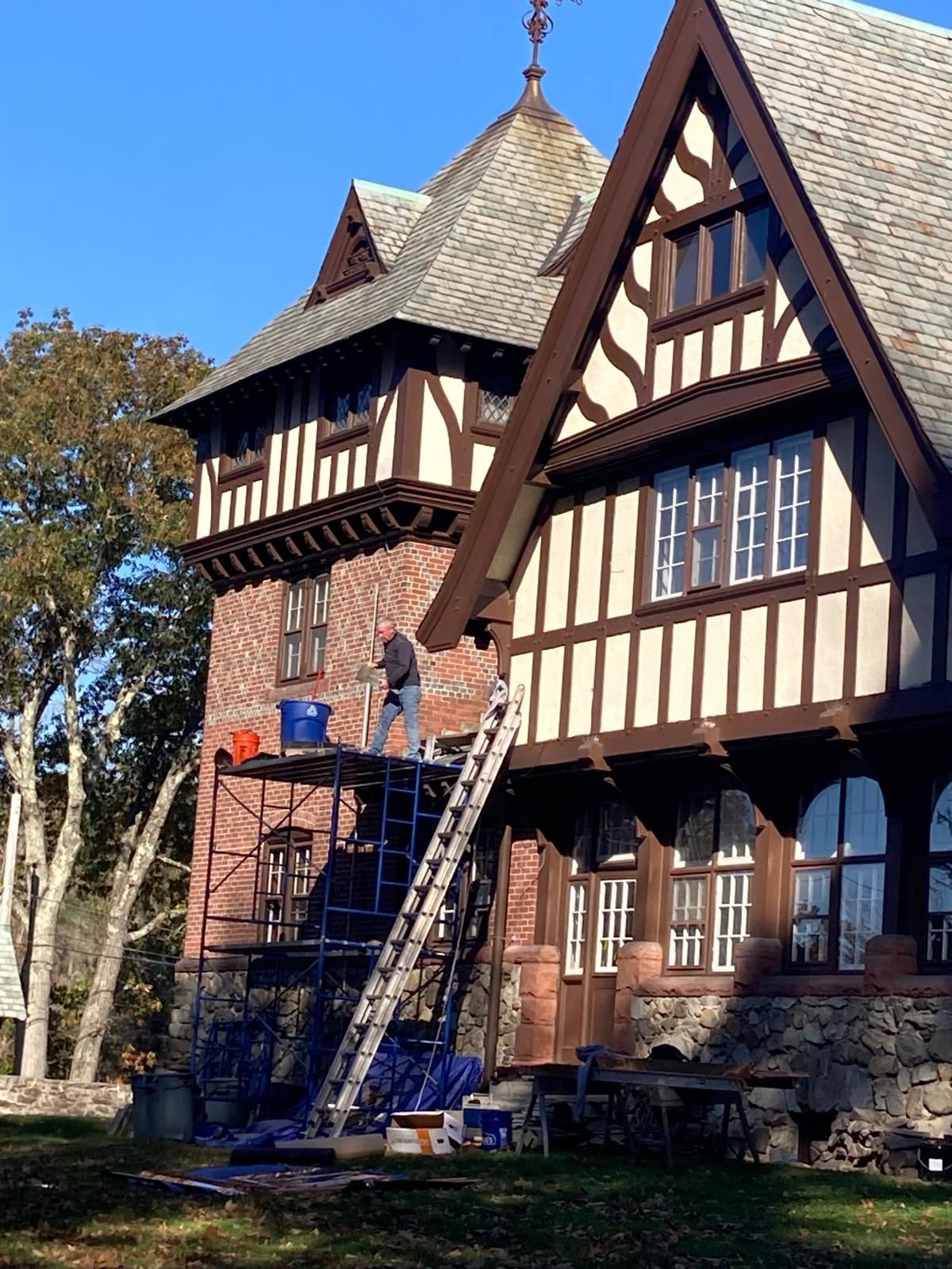 A man standing on a ladder in front of a large house