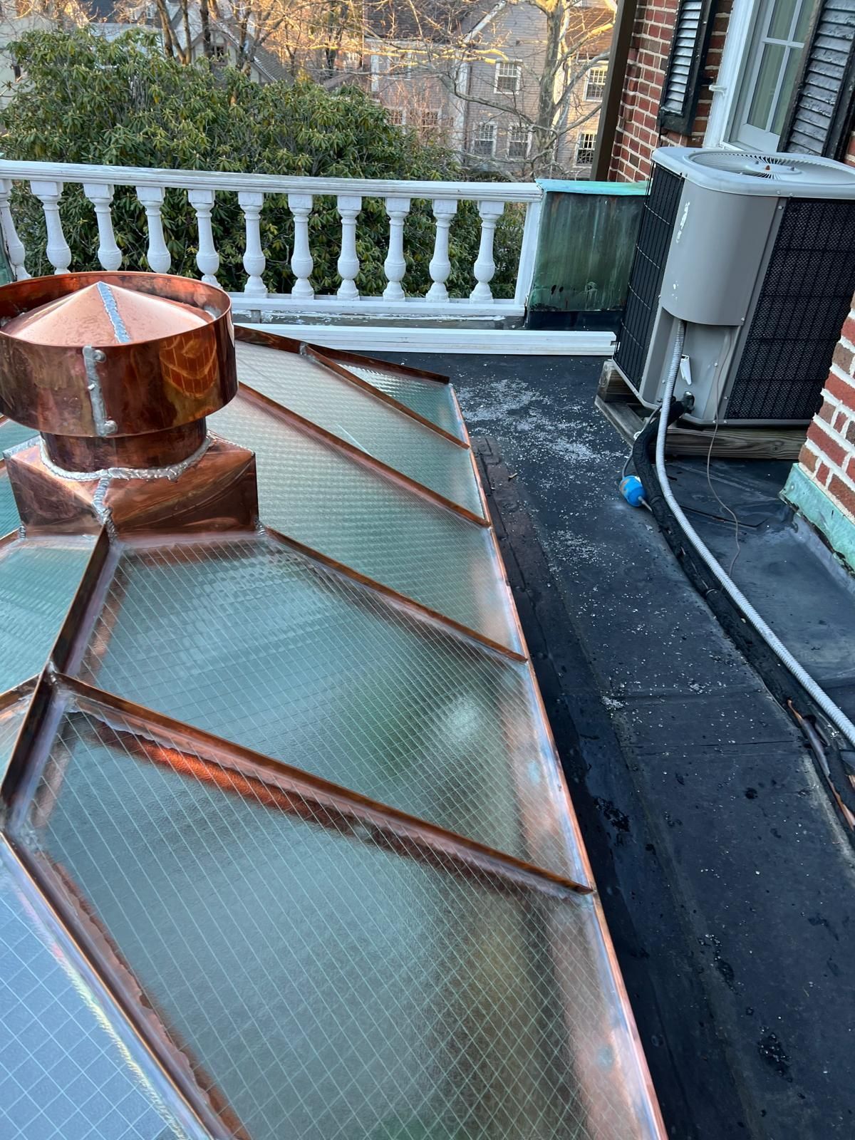 A roof with a copper chimney on top of it.