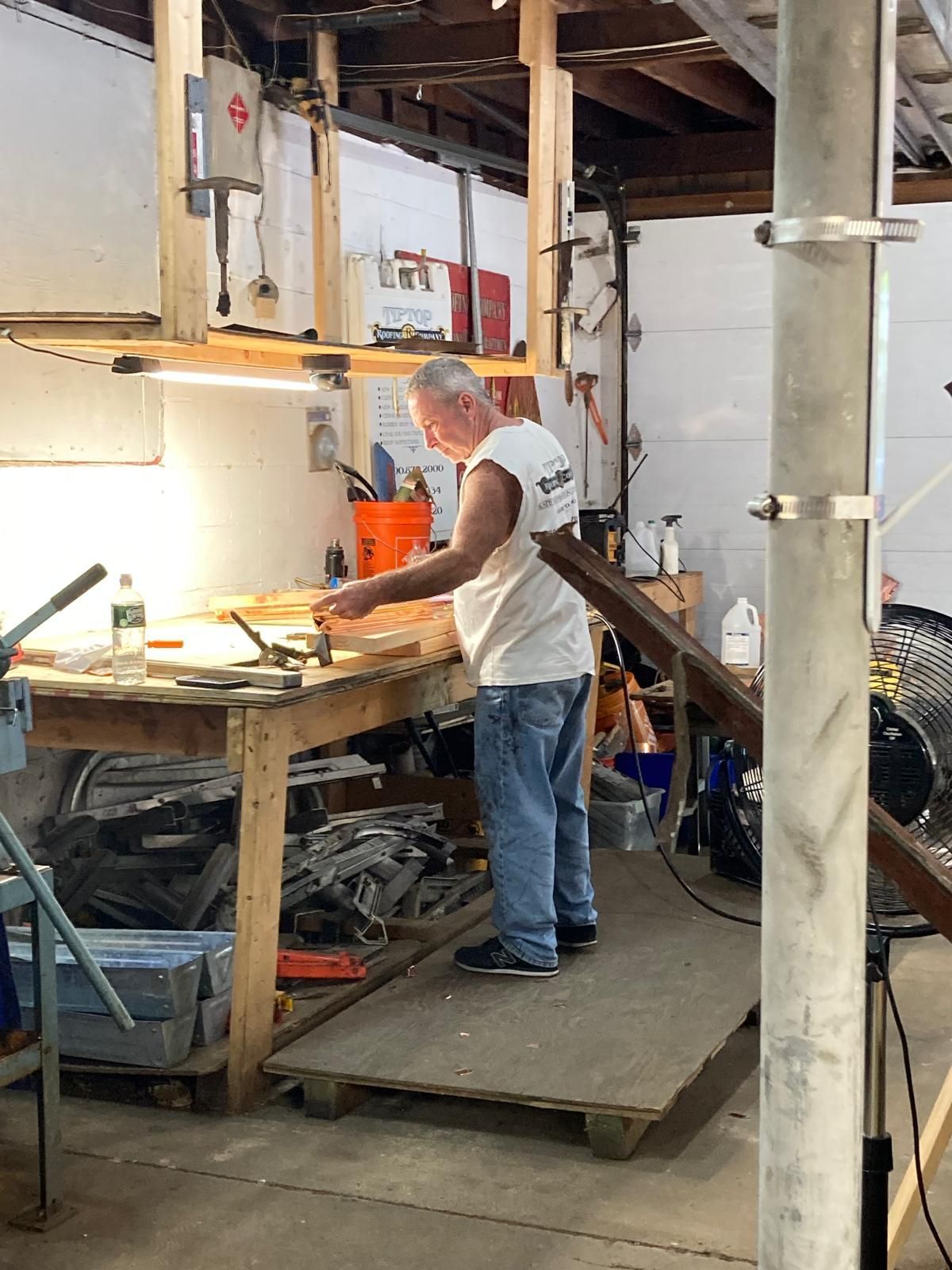 A man is working on a piece of wood in a workshop.