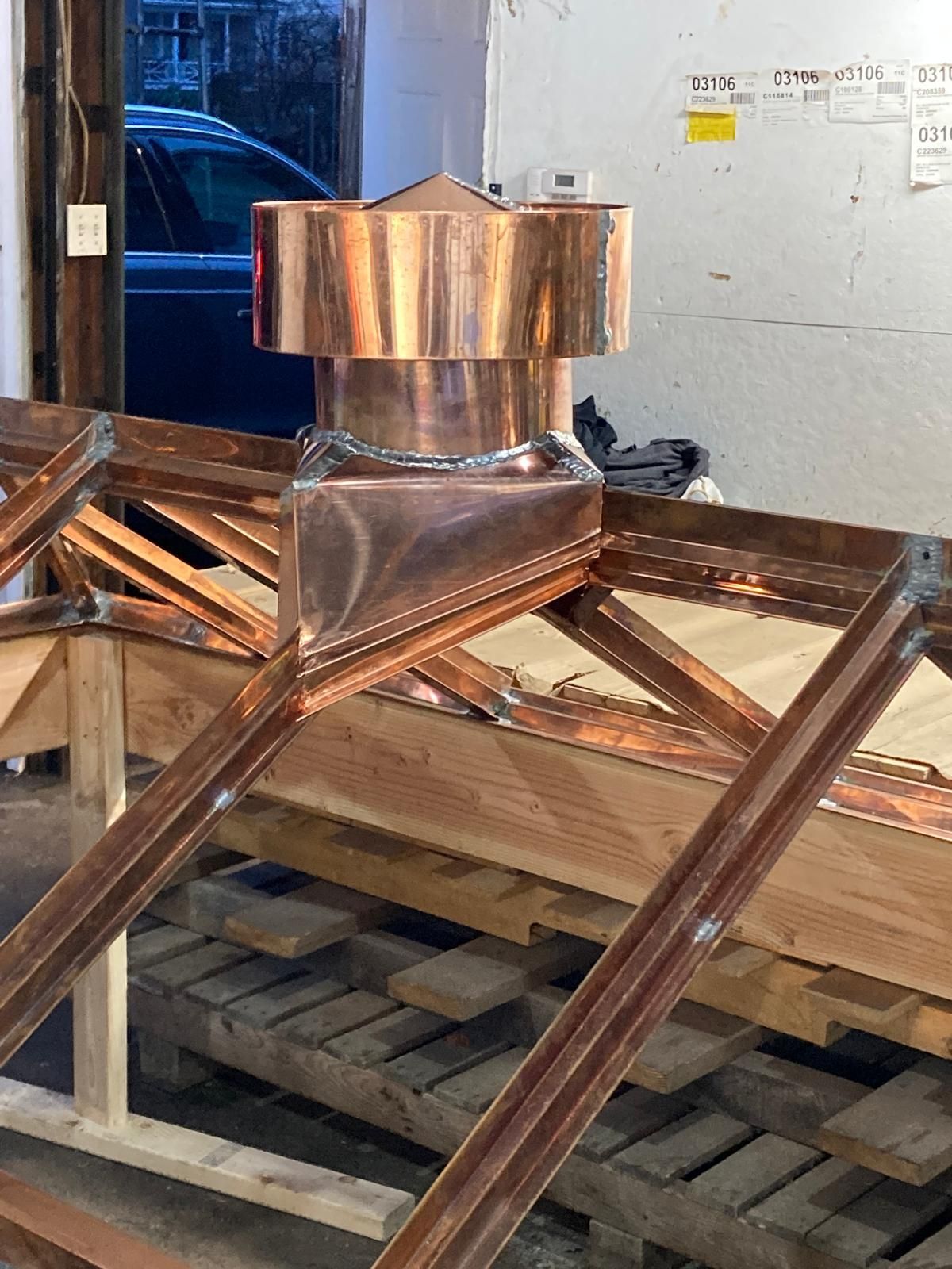 A copper chimney is sitting on top of a wooden structure.