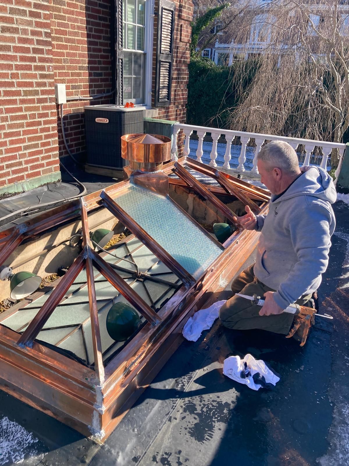 A man is working on the roof of a brick house.