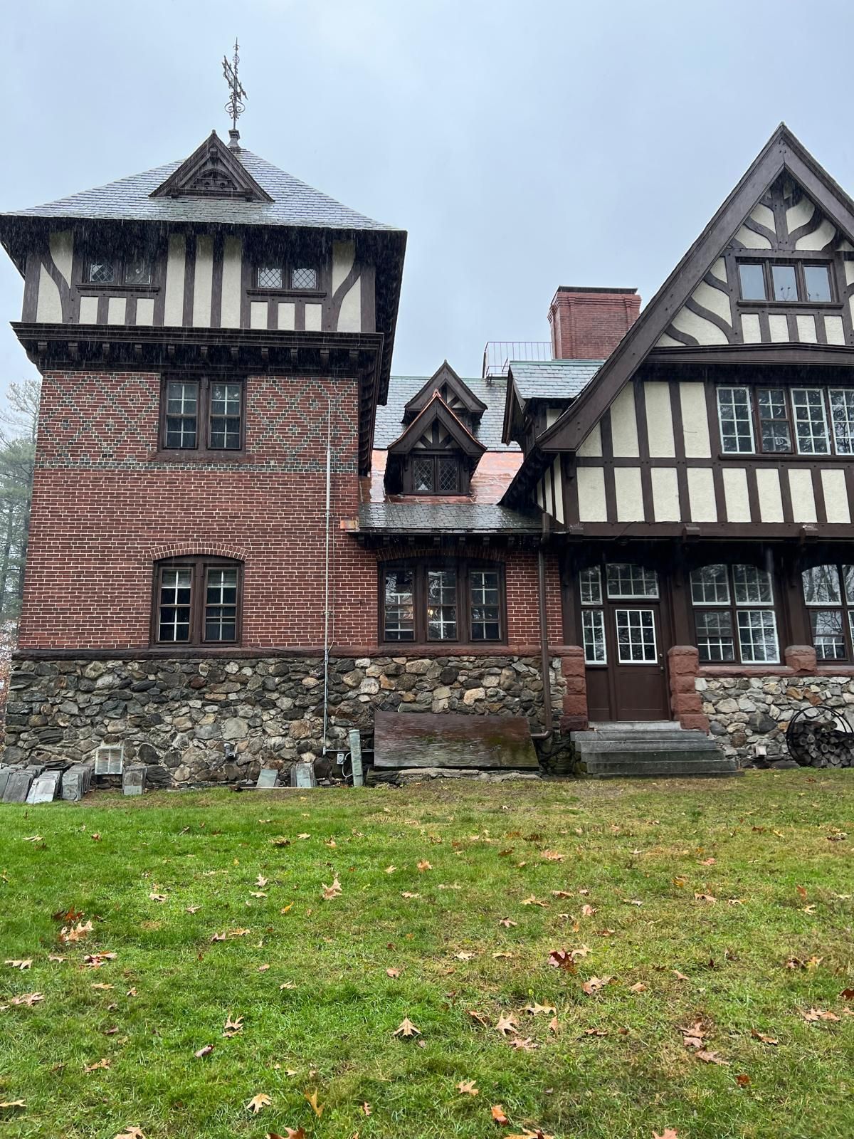 A large brick and wooden house is sitting on top of a lush green field.