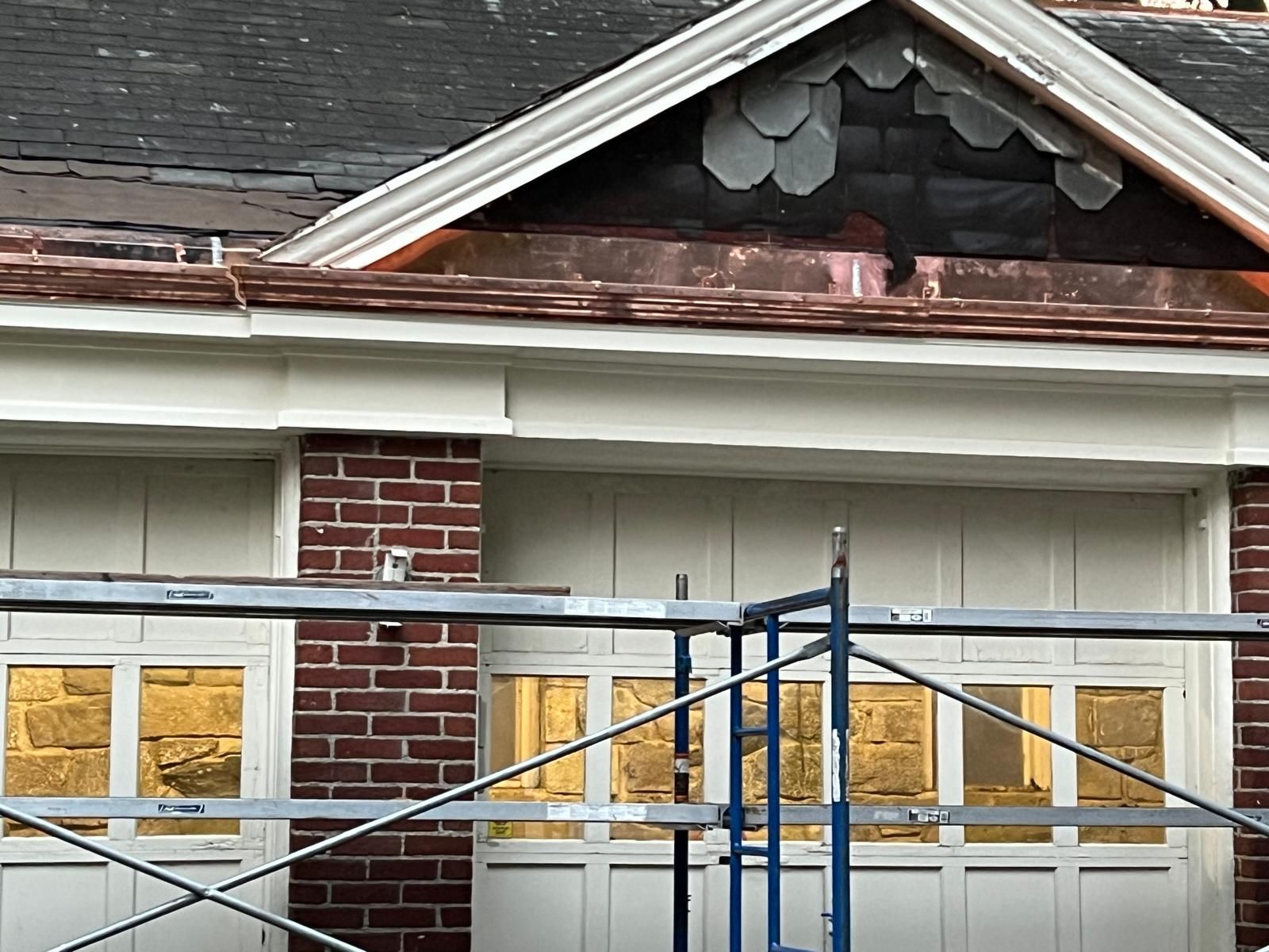 A brick building with a white garage door and a scaffolding in front of it.