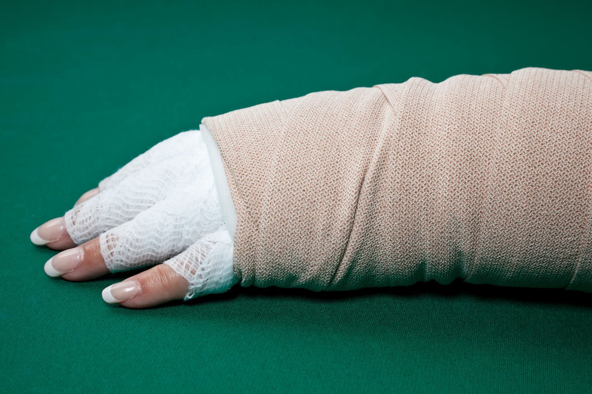Hand wrapped in bandages on a green surface.