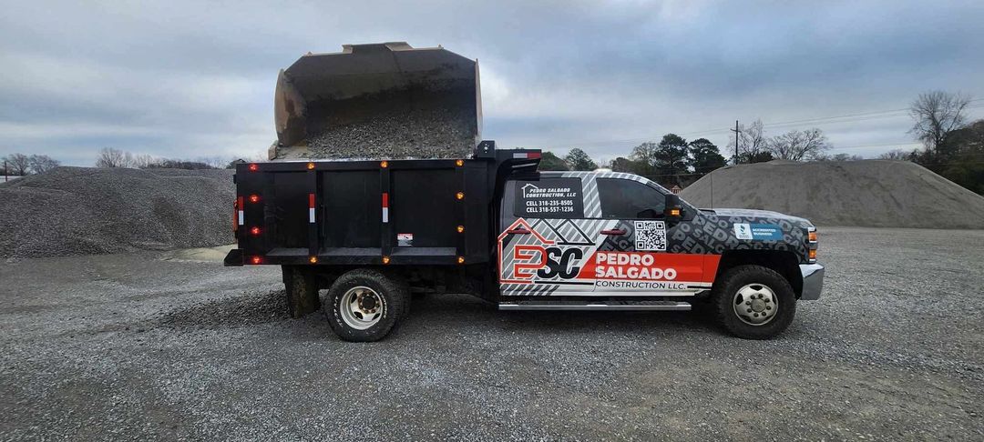 A dump truck is parked in front of a pile of gravel.