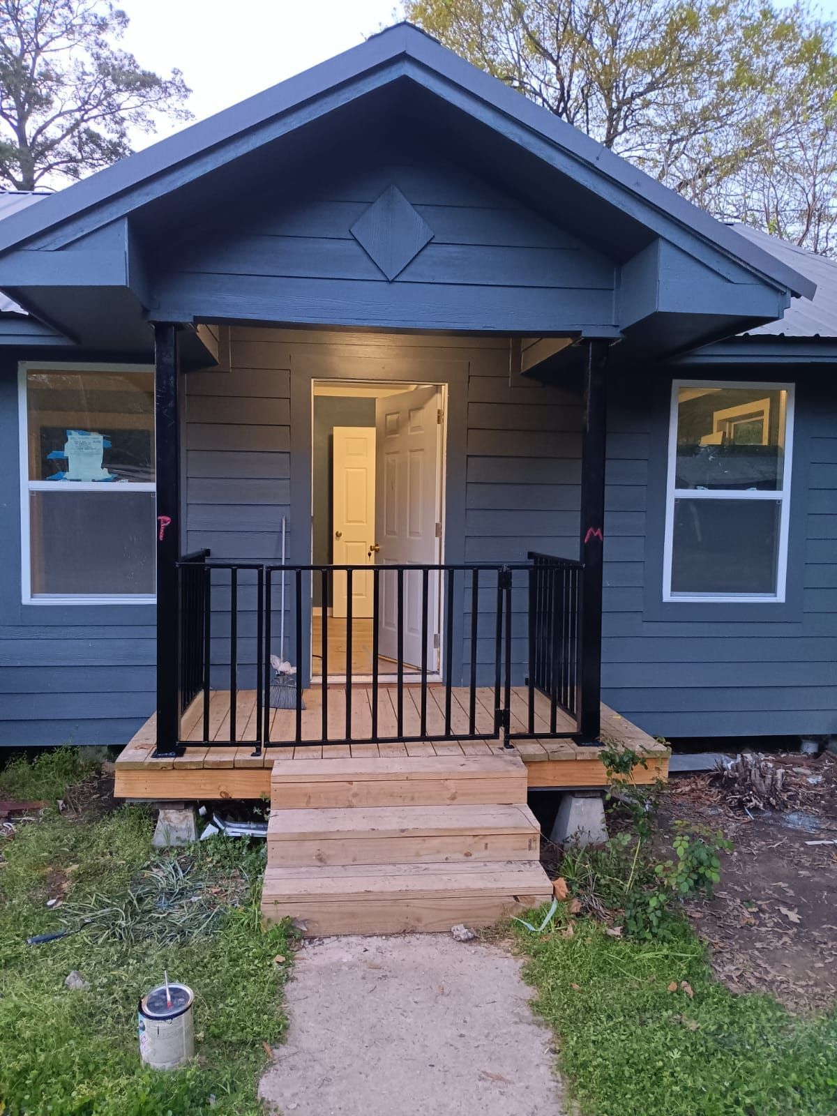 A small blue house with a porch and stairs