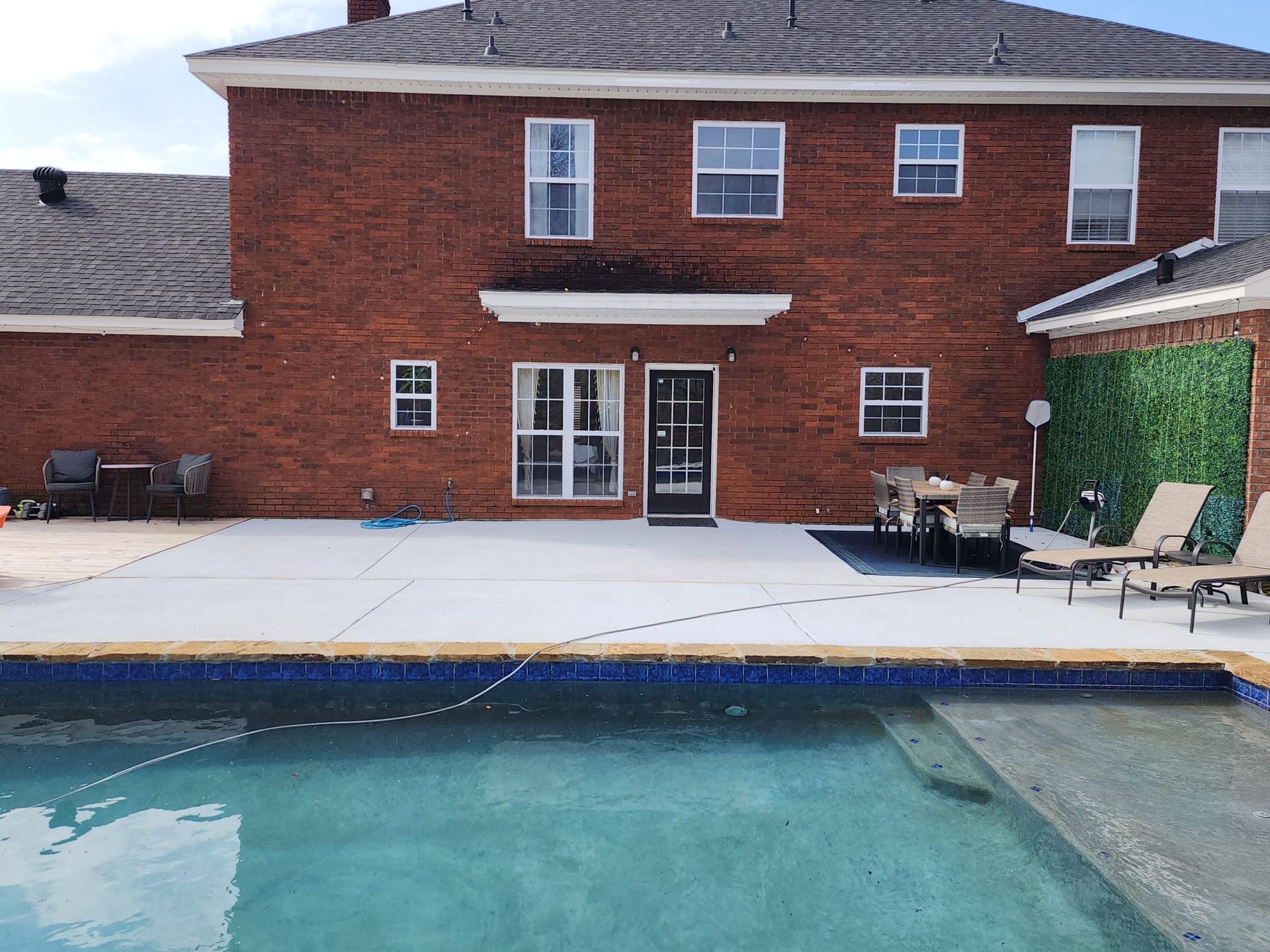 A large brick house with a swimming pool in front of it.