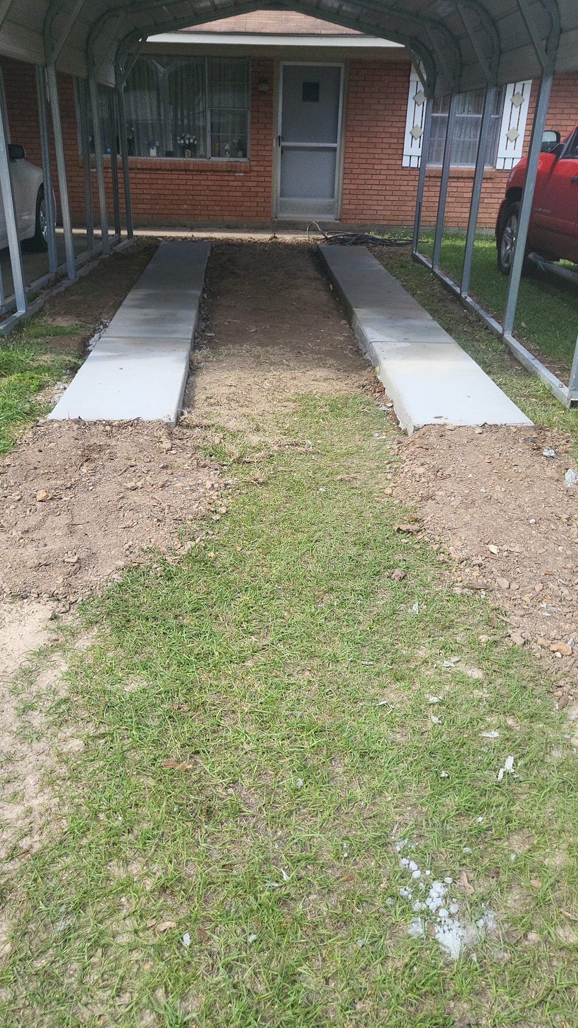 A concrete driveway is being built in front of a brick house.