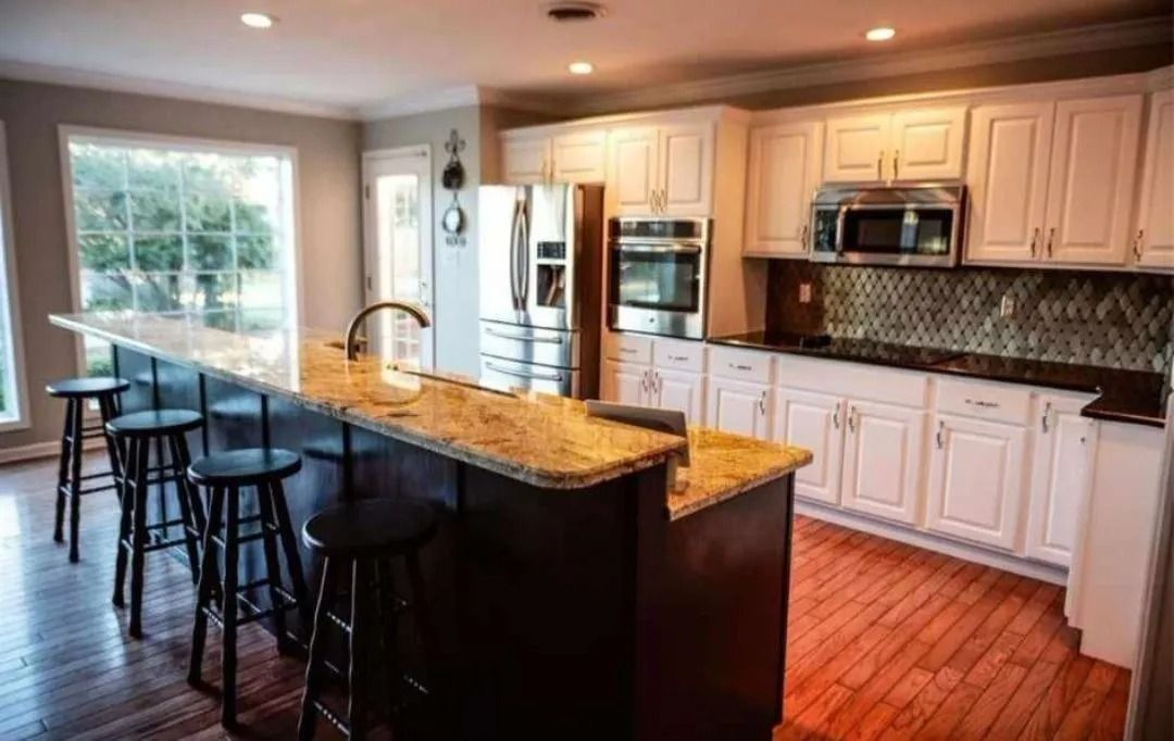Kitchen with a counter bar and stools, white cabinets, stainless steel appliances, and a window.