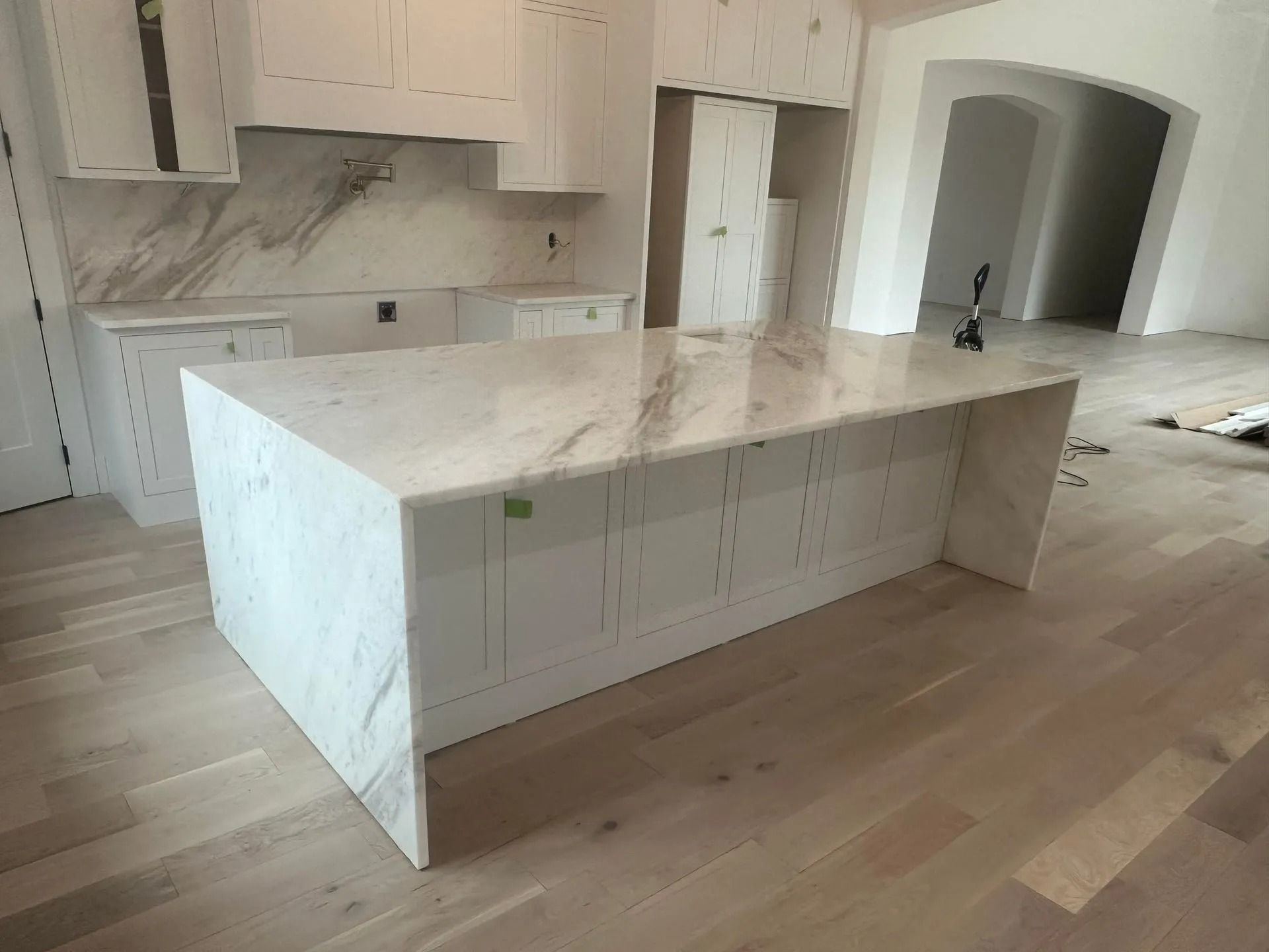 Kitchen with white cabinetry, marble countertops, and a large island.