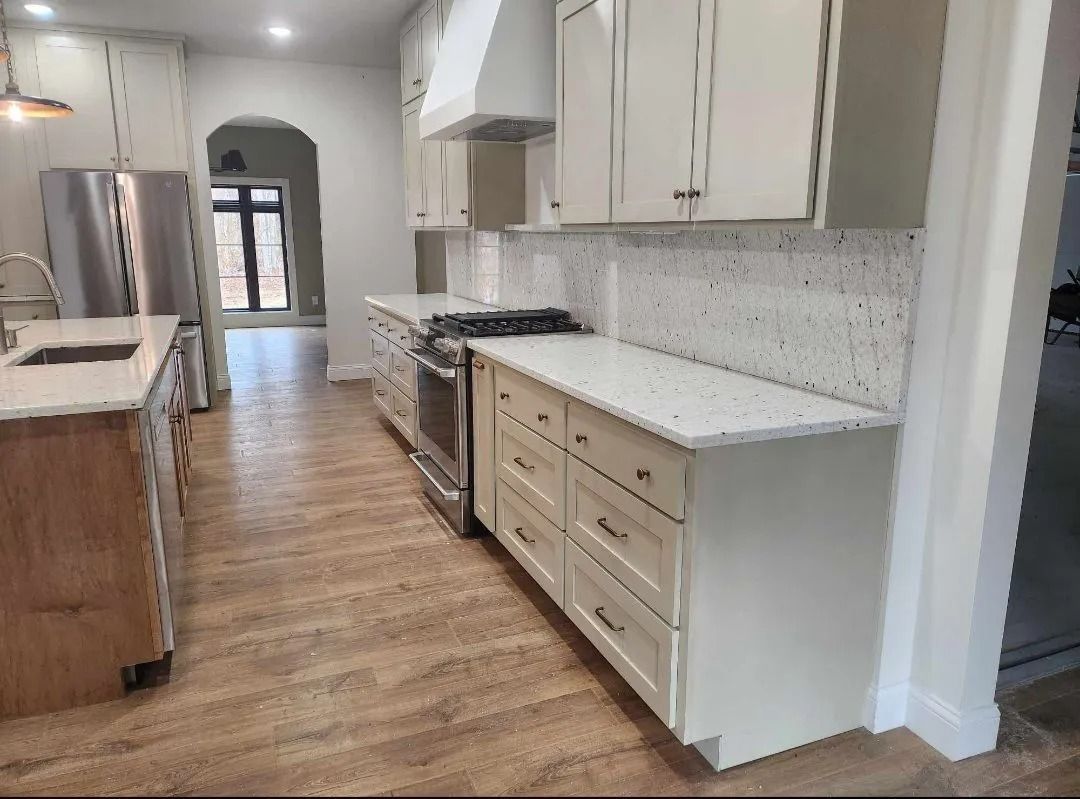 Kitchen with light cabinets, speckled countertops, stainless steel appliances, and wood flooring.