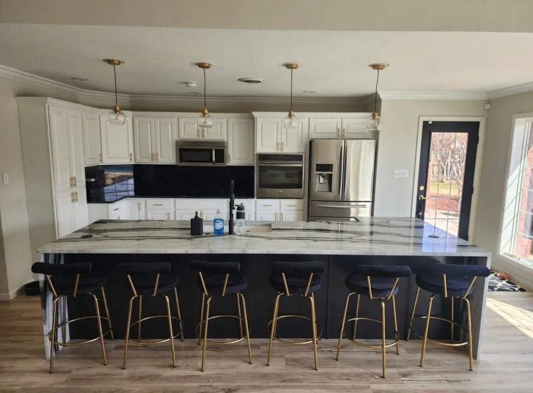 Modern kitchen with island, white cabinets, black countertops, and gold accents.