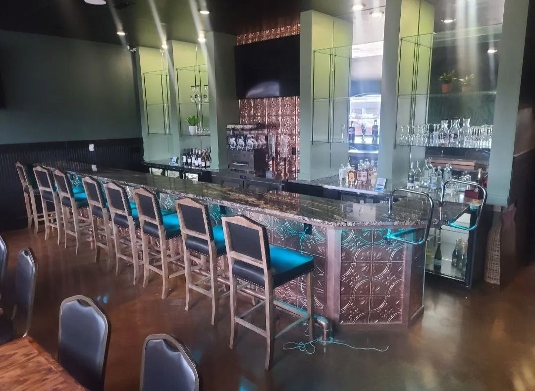 Bar with teal stools, copper accents, and bottles on shelves.
