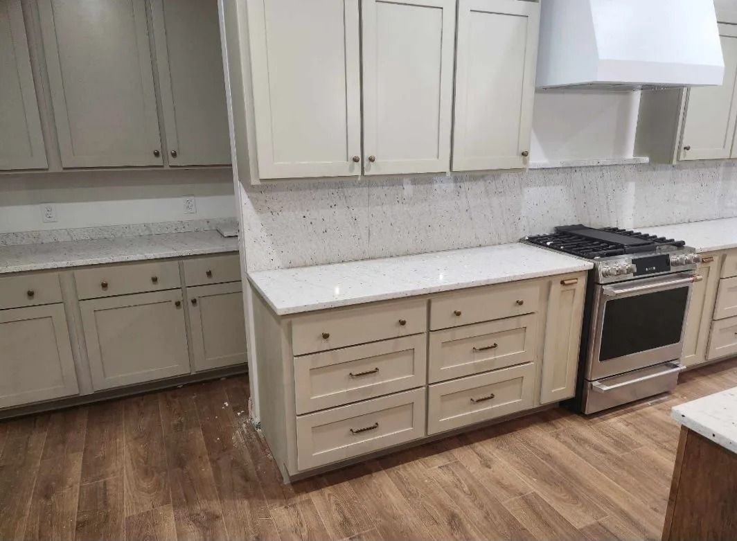 Cream-colored kitchen cabinets with quartz countertops and stainless steel oven and range.