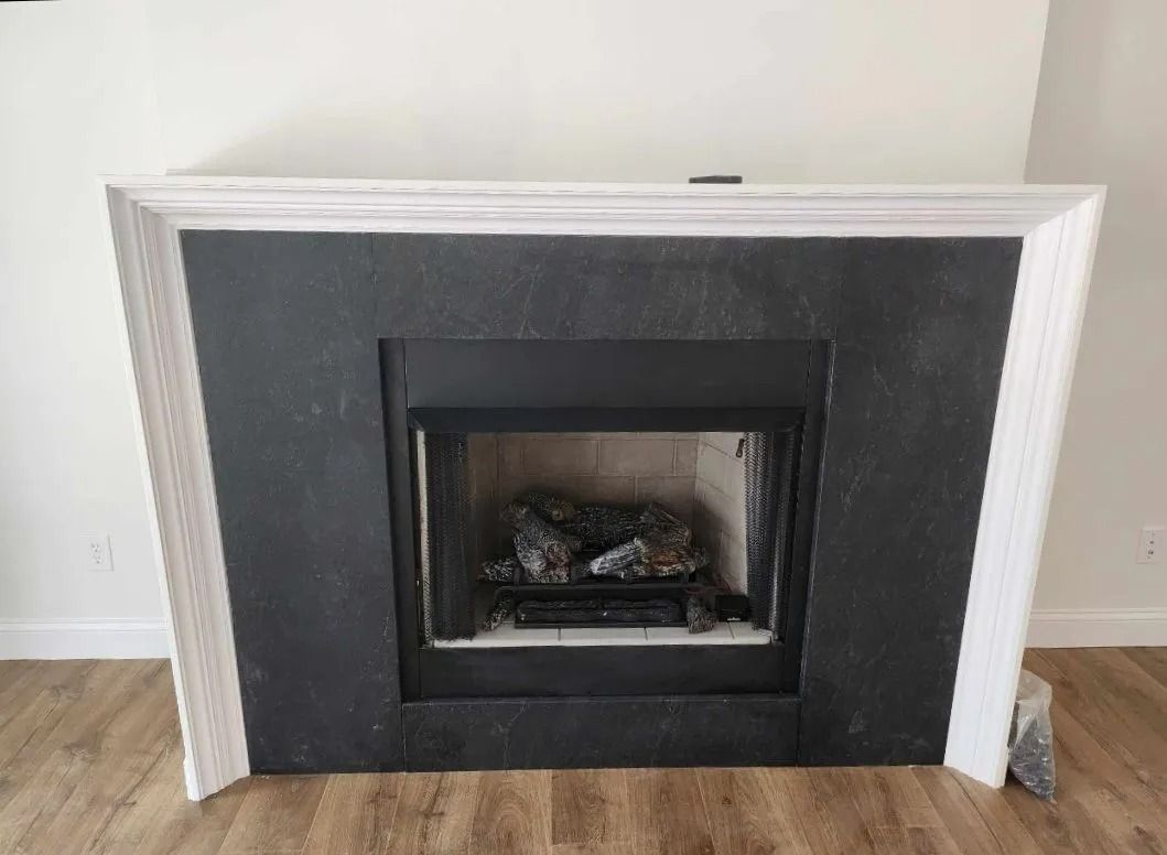 Fireplace with black surround and white mantel against a light wood floor.