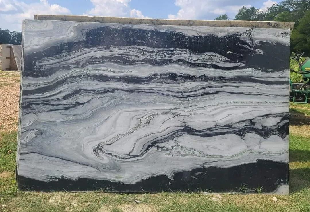 Large marble slab with swirling black and gray patterns, outdoors.