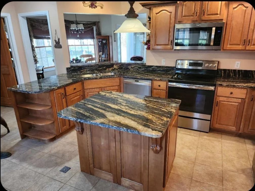 Kitchen with granite countertops and wooden cabinets, featuring a center island and stainless steel appliances.