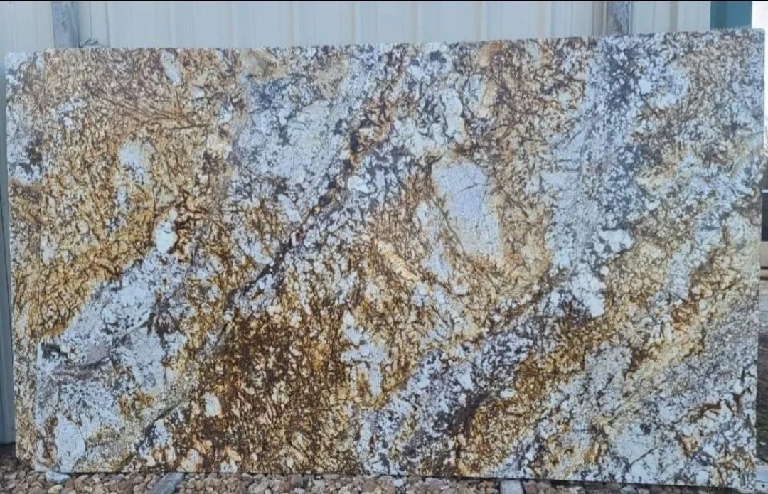 Large slab of golden, white, and gray granite with flowing patterns.