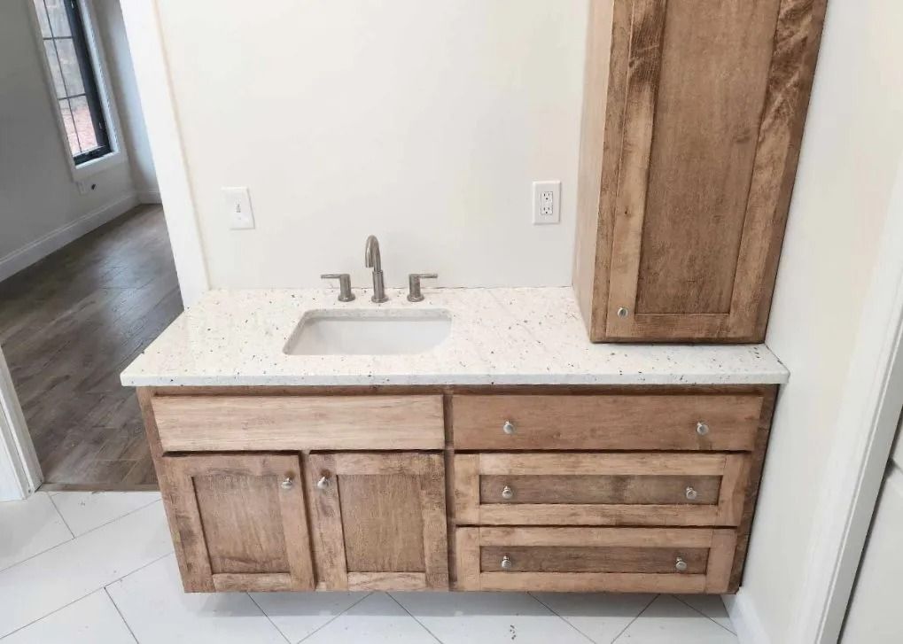 Bathroom vanity with sink, drawers, cabinets, and a tall cabinet; light wood tones.