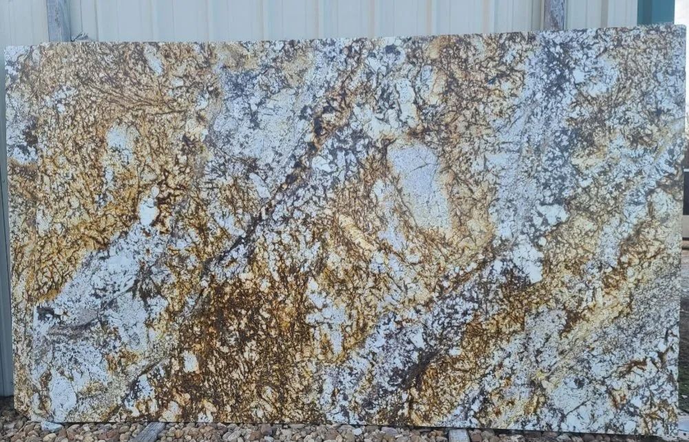 Large granite slab with a complex pattern of gold, white, and brown swirls.
