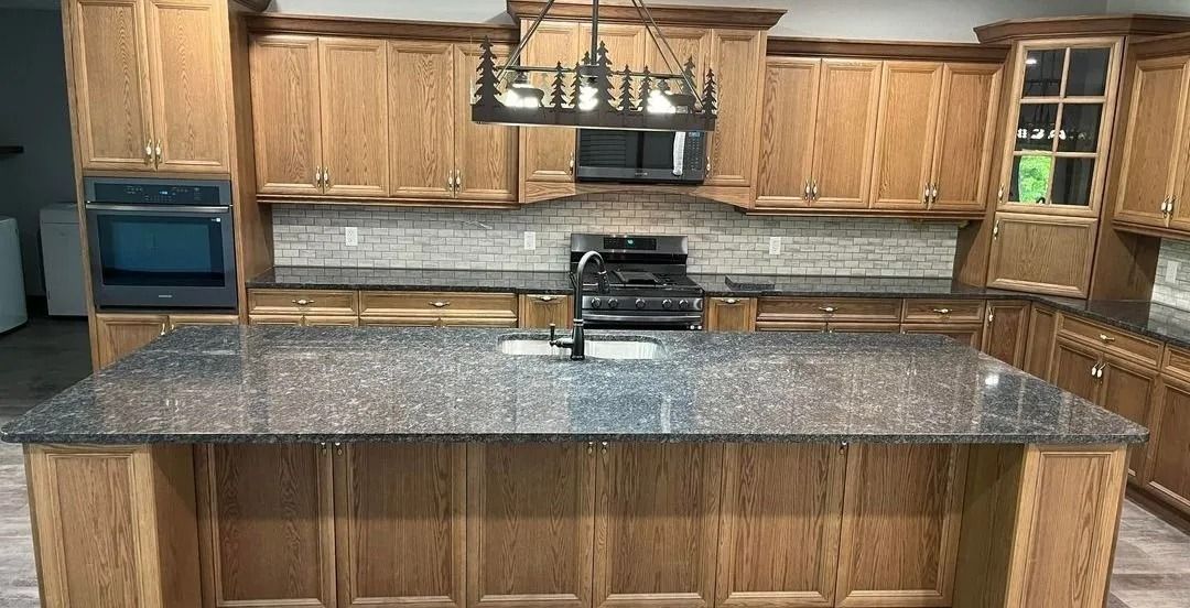 Kitchen with light-brown cabinets, dark countertop, stovetop, and overhead light.