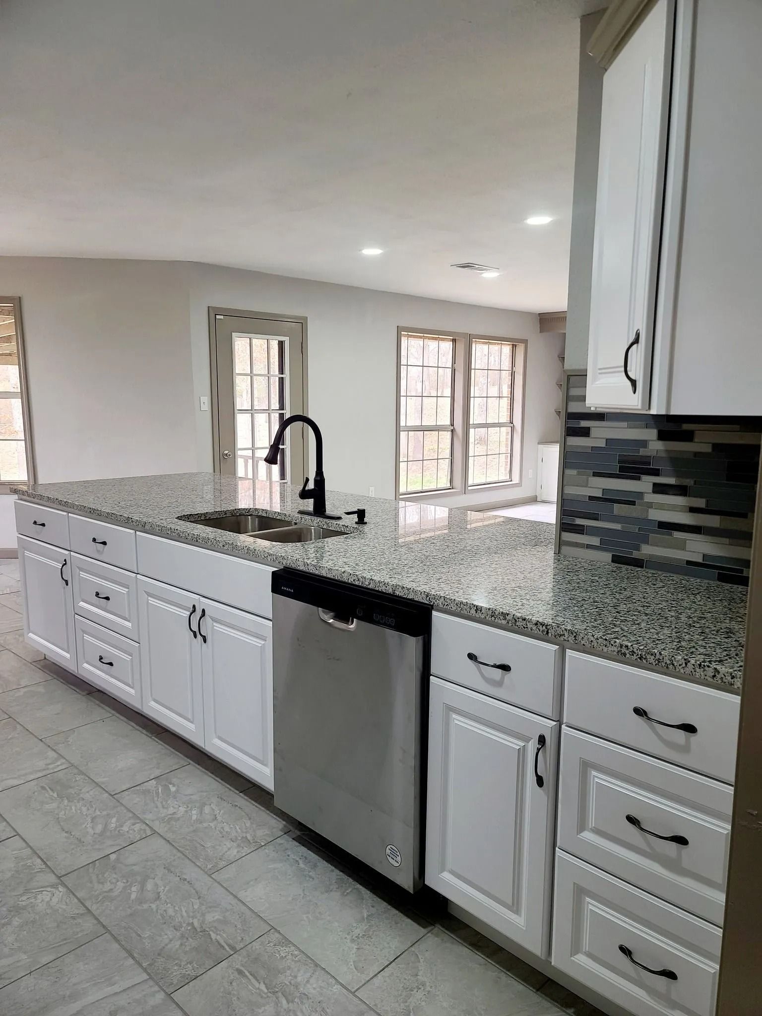 White kitchen with granite countertops, stainless steel appliances, and black hardware.