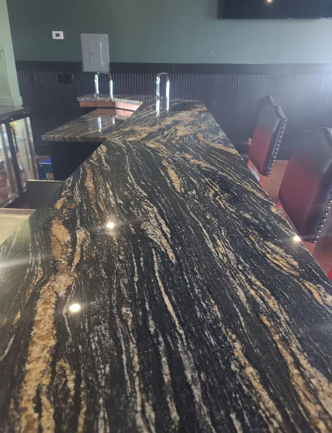 Bar countertop with black, gold and brown veined granite, restaurant setting.